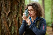 Eine Forstreferendarin verwendet ein forstliches Messinstrument im Wald