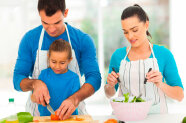 Paar und Kind bereiten gemeinsam Salat zu 